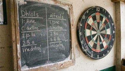 Krijtbord met twee aftellende kolommen naast een dartbord, krijtstof op de rand.