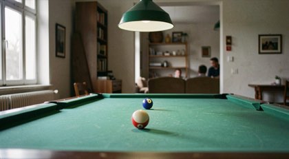 Biljarttafel met groen laken en drie ballen, hanglamp laag boven het speelvlak.