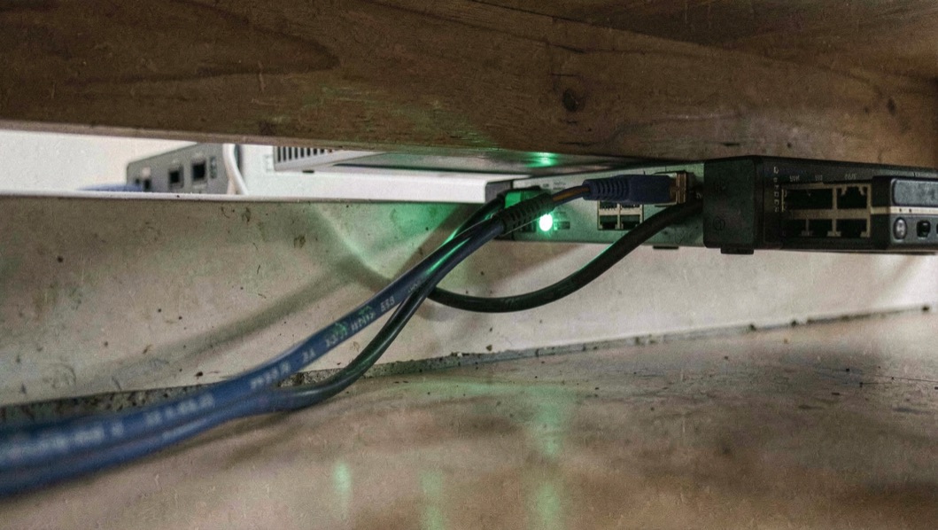 Netwerkkabel gestoken in een router onder een bar, lampjes groen, kabels netjes langs de plint.