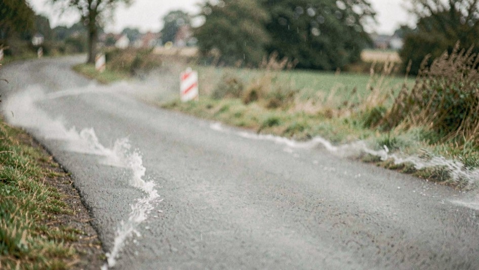 Renners schuin over de weg in zijwind, de sliert loopt van de ene berm naar de andere.